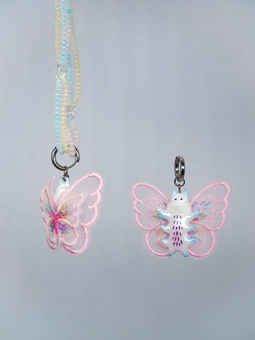 Butterfly cat necklace and earring set in pearlescent white with pink, purple, and blue accents.