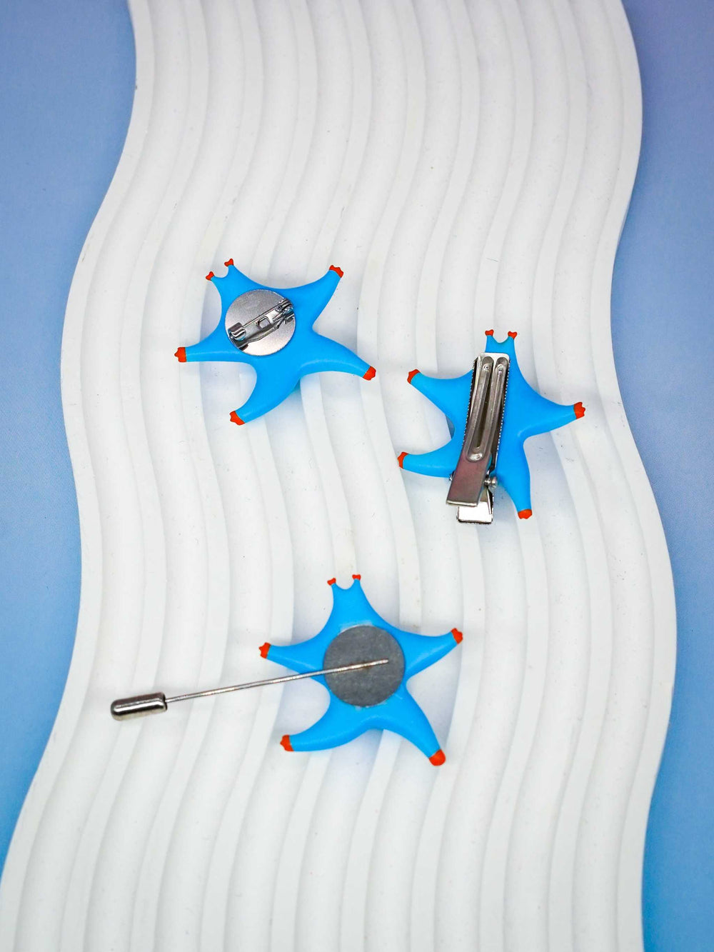 SeaStar cat hairclip and brooch in magenta and navy colors on a textured background.