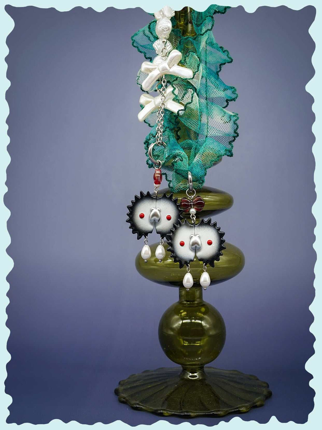 Venus flytrap necklace and earrings with black edge and silver fly design displayed on green stand.