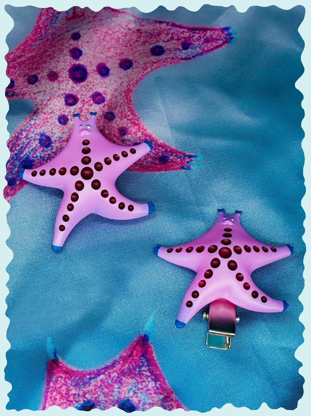 SeaStar cat hairclip and brooch in magenta and navy with pearl color blocking on fabric background.