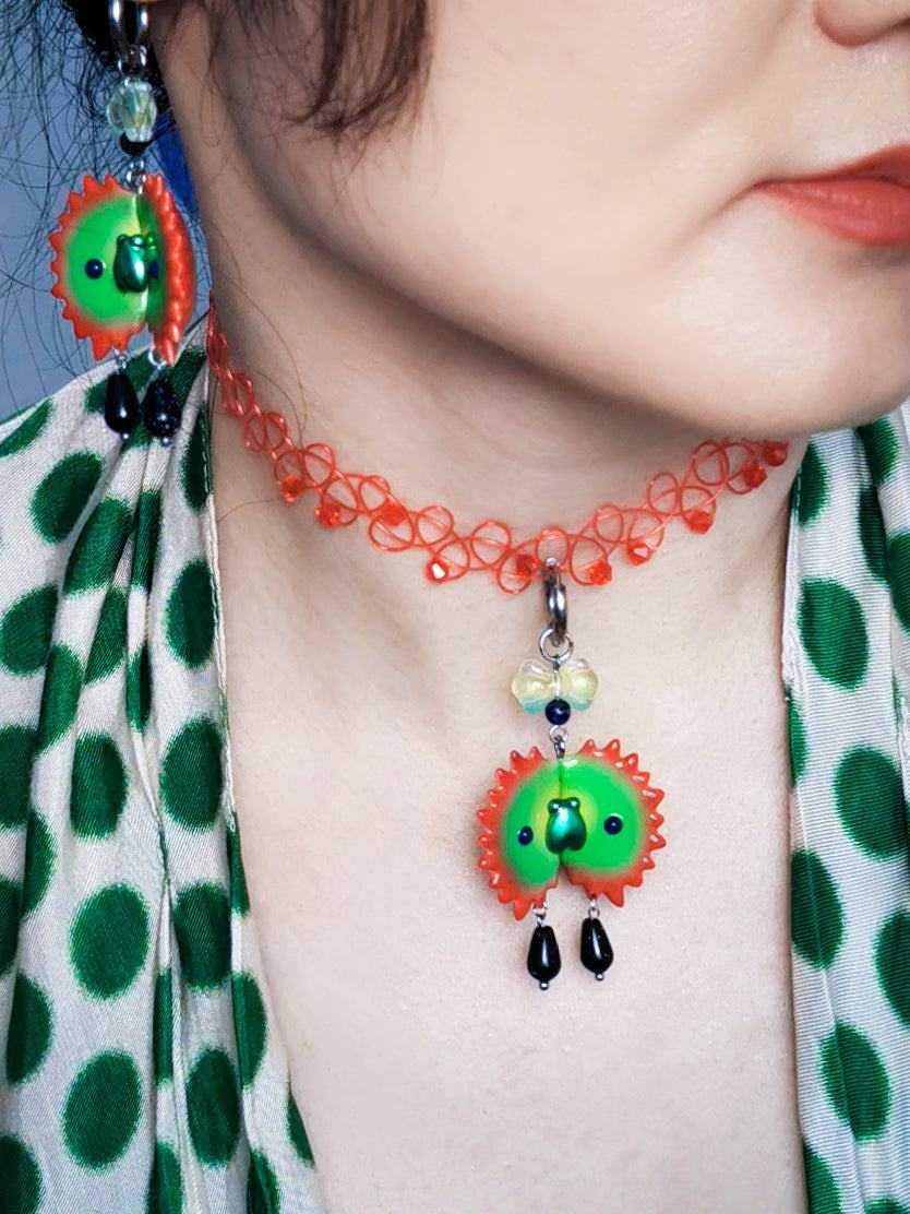 Venus flytrap necklace and earring set with green fly design on model.