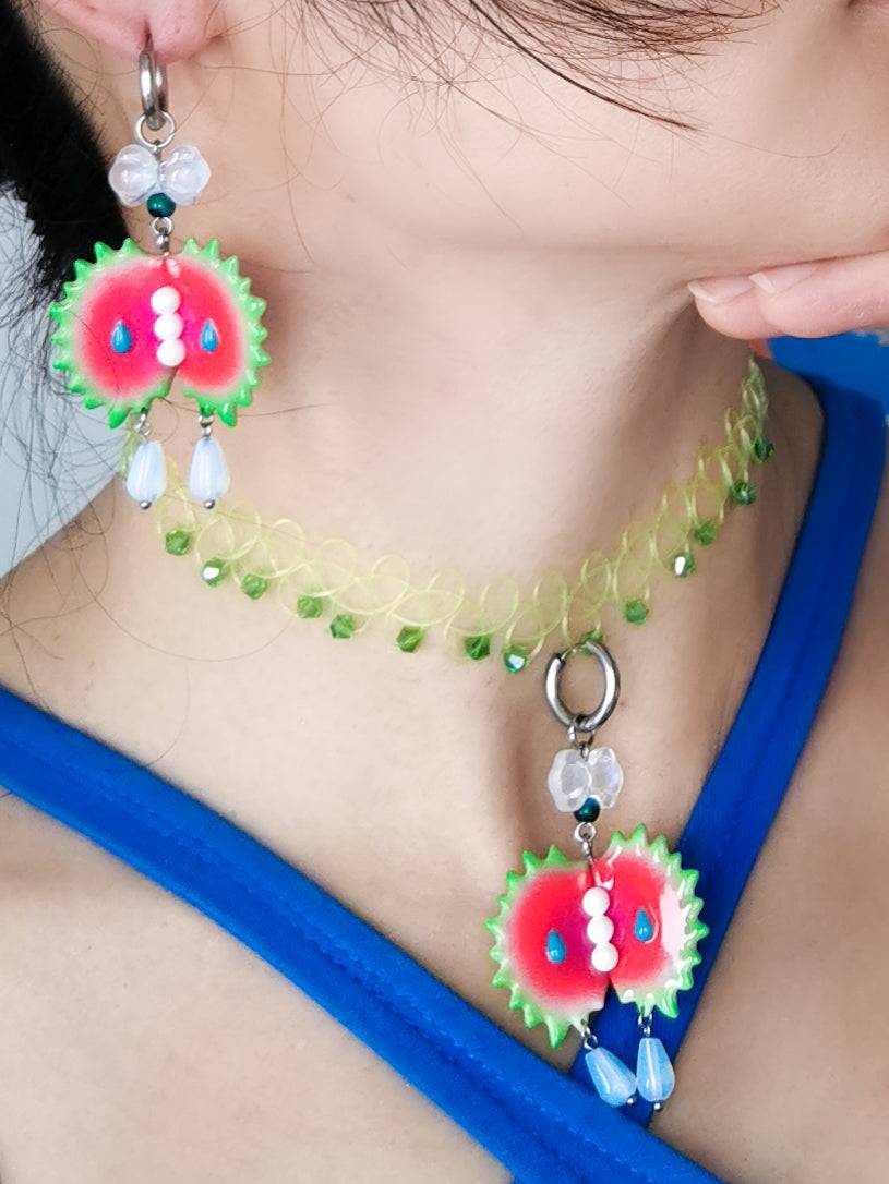 Venus flytrap necklace and earrings with green edge and pearl middle on model.