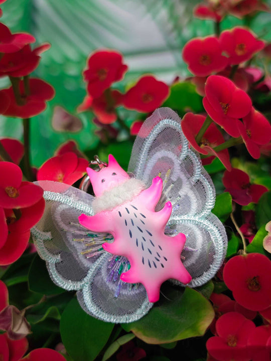 Butterfly cat with flamingo pink body and mint green wings in a flower scene.