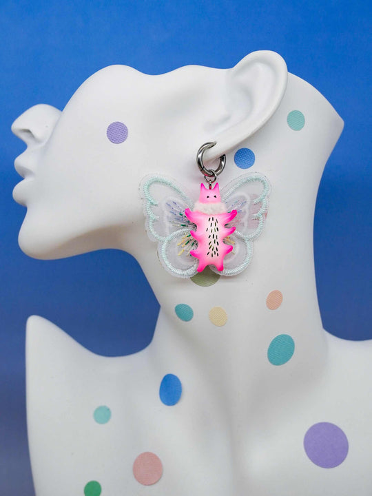Butterfly cat with flamingo pink body and mint green wings earring on mannequin.