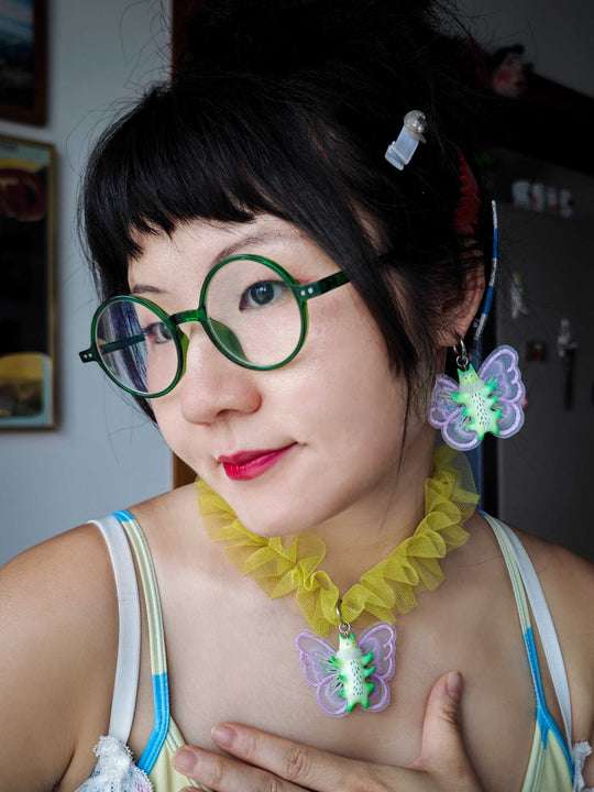 Butterfly cat necklace and earring set in green and purple worn with a yellow fur snood.