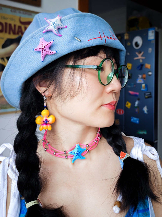 Magenta and navy cat-shaped SeaStar hairclip and brooch worn on a hat.